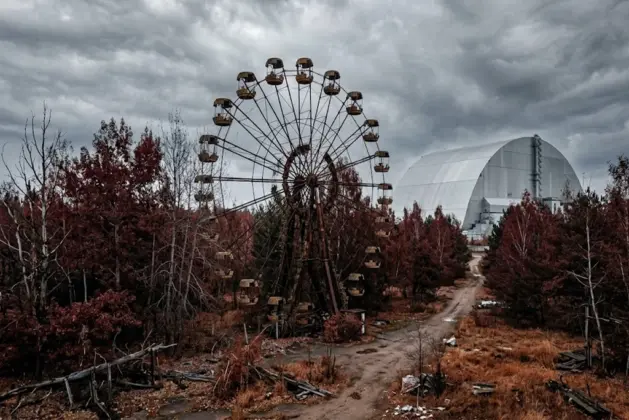 “Chernóbil datos curiosos: vista realista del Bosque Rojo con la rueda de la fortaleza abandonada y el nuevo sarcófago, mostrando la zona de exclusión.”