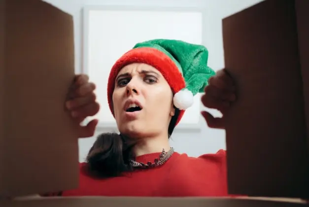 Mujer abriendo uno de los regalos debajo del árbol que nadie quiere ver