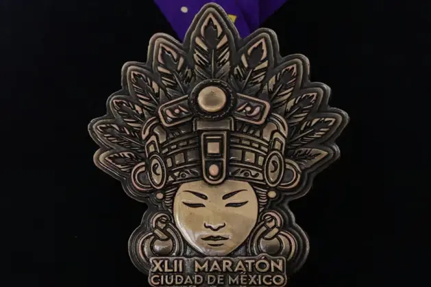 Medalla Maratón de la CDMX 2025 inspirada en Cihuacóatl, diosa mexica mujer serpiente, sobre fondo de textura prehispánica.