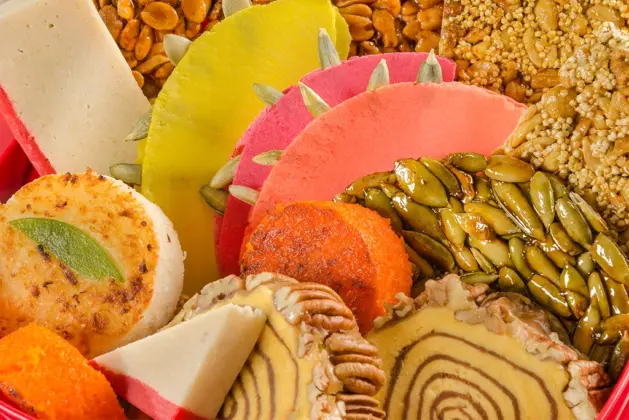 Variedad colorida de dulces típicos mexicanos como alegrías, cocadas, jamoncillos y camotes, dispuestos para celebrar las Fiestas Patrias.