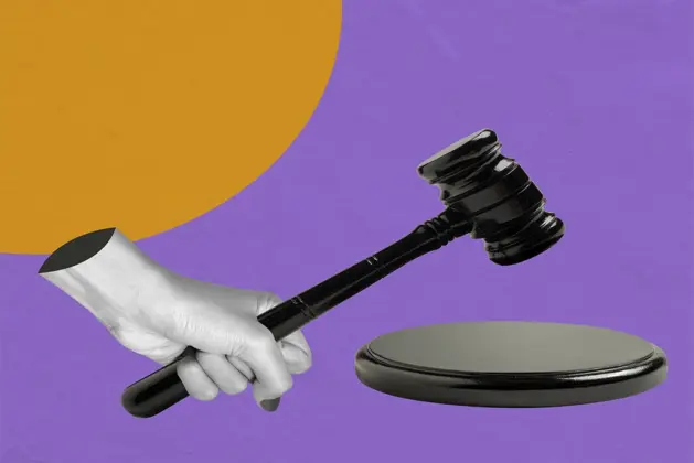 Una mano sosteniendo un mazo de juez sobre un fondo colorido, representando el concepto de leyes raras en el mundo.