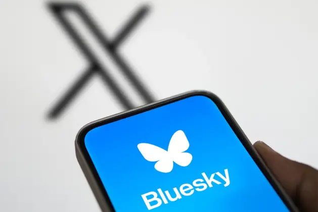 Un teléfono con la imagen de la nueva red Bluesky que gana terreno y de fondo el logo de X, la red con la que compite.