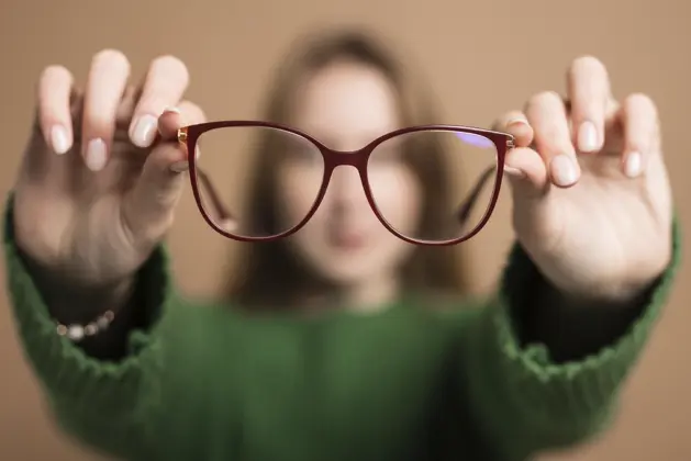 Joven mostrando lentes en primer plano, con miopía, considerando hacer ejercicios para tratarla