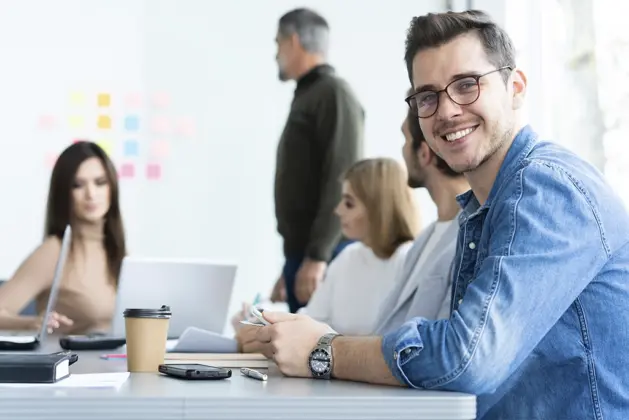 Estudiante sonriente interactuando en un entorno profesional, representando las carreras de trato con personas donde la comunicación y el servicio son clave.