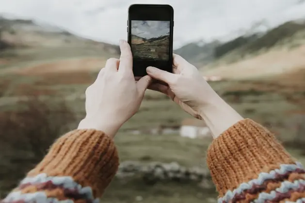 Joven universitario utilizando un smartphone para realizar fotografía móvil profesional en un entorno urbano, celebrando el Día Mundial de la Fotografía