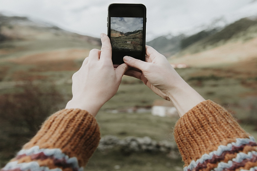 Joven universitario utilizando un smartphone para realizar fotografía móvil profesional en un entorno urbano, celebrando el Día Mundial de la Fotografía