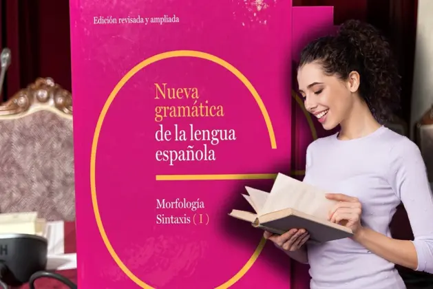 Mujer sonriente leyendo un libro frente a un ejemplar destacado de la Nueva gramática de la lengua española, edición revisada y ampliada.