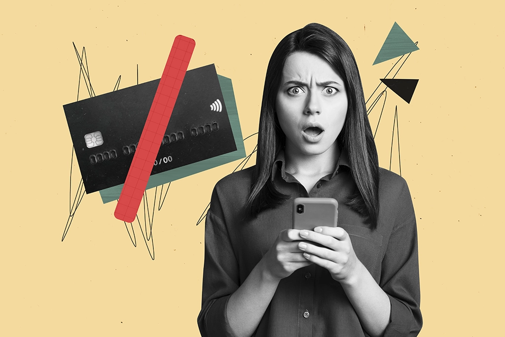 Mujer sorprendida al revisar los diferentes tipos de gastos en su celular, con una tarjeta de crédito en el fondo.