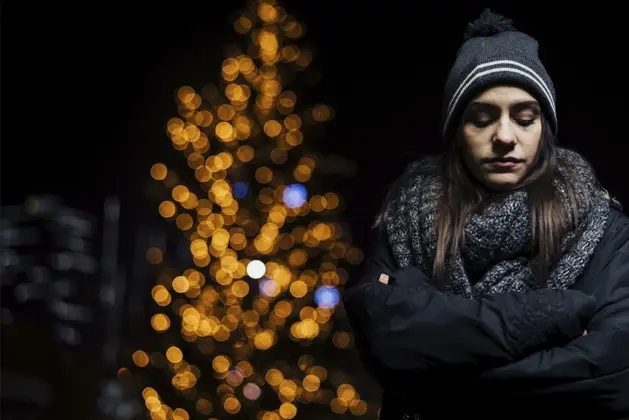 Mujer triste durante la noche de invierno, representando los efectos del trastorno afectivo estacional, una condición relacionada con la falta de luz solar.