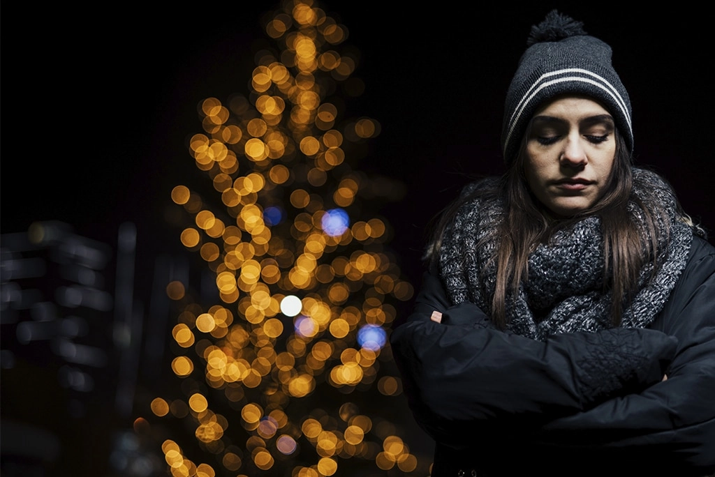 Mujer triste durante la noche de invierno, representando los efectos del trastorno afectivo estacional, una condición relacionada con la falta de luz solar.