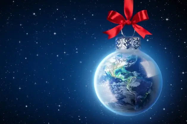 Esfera navideña en forma del planeta Tierra con un lazo rojo, representando la diversidad de costumbres navideñas del mundo bajo un cielo estrellado.