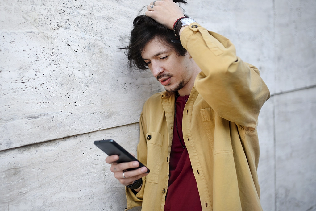 Joven universitario mirando con sorpresa la pantalla de su smartphone que muestra una alerta de datos agotados, con consejos visuales para ahorrar datos móviles