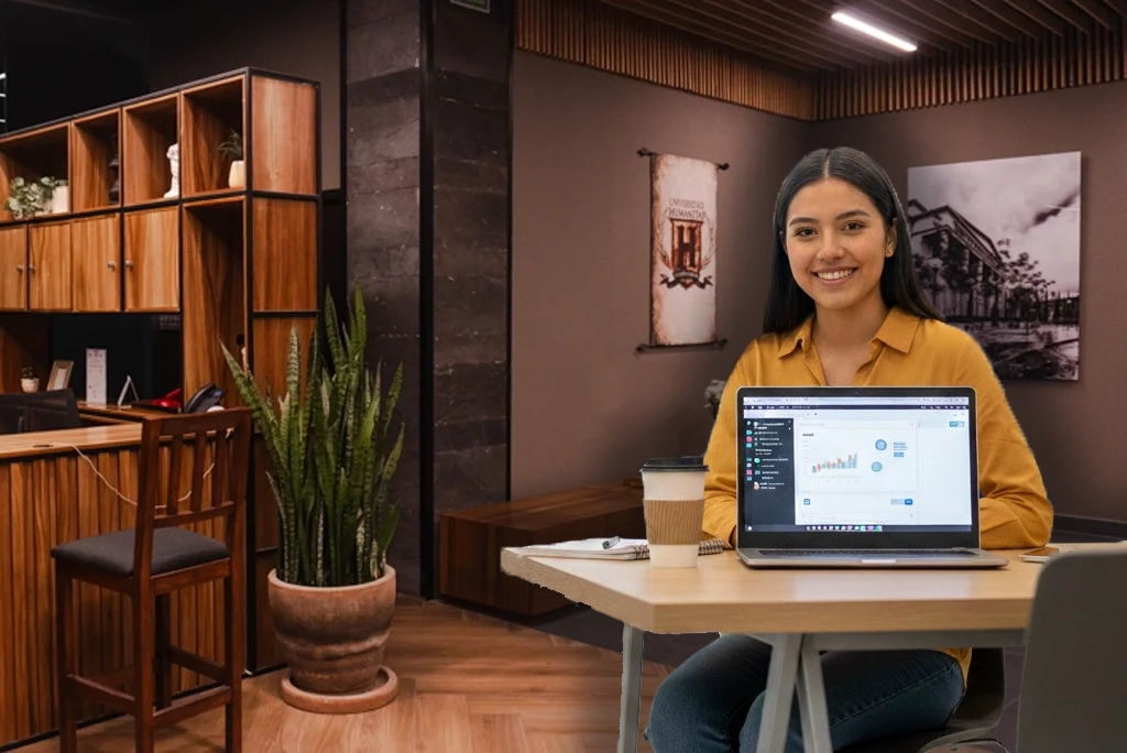 Estudiante sonriente utilizando una laptop en un espacio moderno, representando la flexibilidad y modernidad de los nuevos modelos educativos en universidades mexicanas