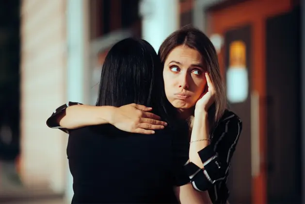 mujer abrazando a otra con mala cara, cayendo en comportamientos de amistades tóxicas.